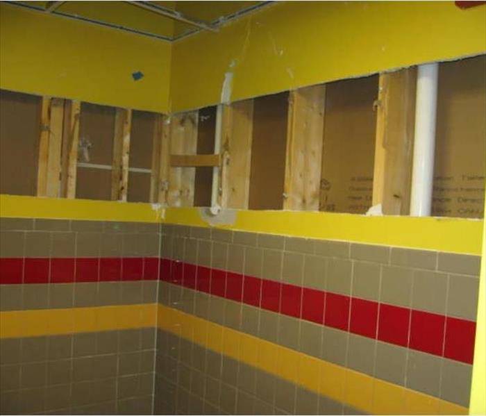 yellow bathroom wall with drywall cut out for drying